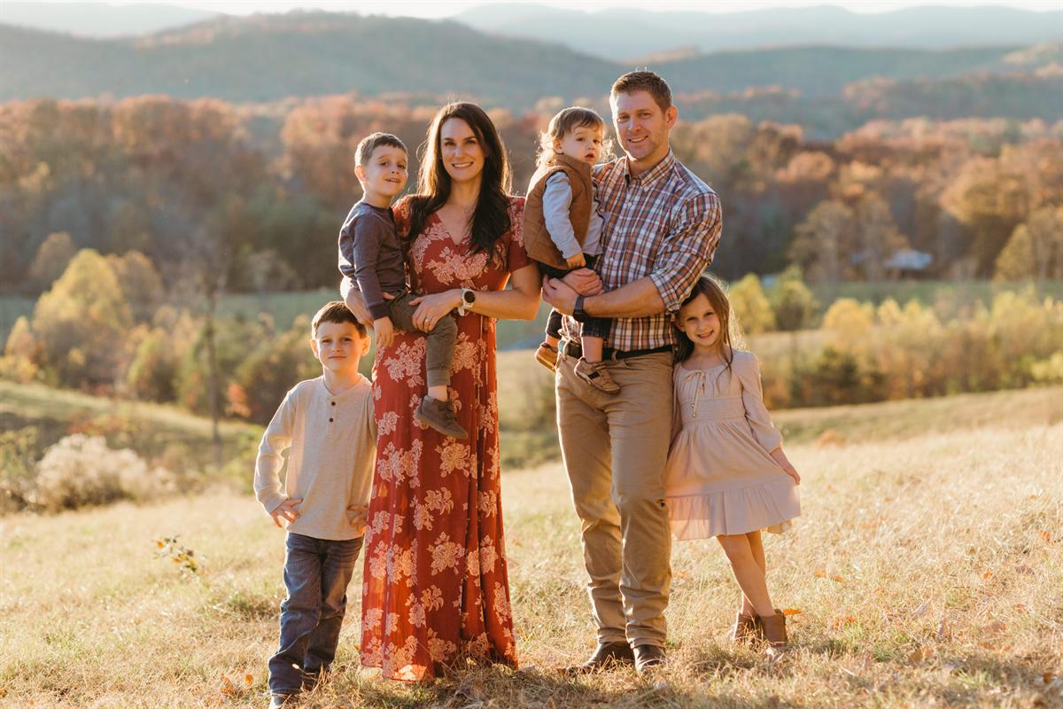 The family at Mountain Valley Farms in the pasture with the Blue Ridge foothills behind them